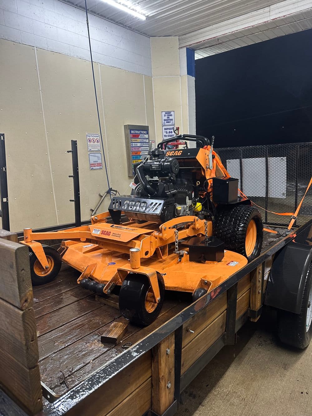 Commercial zero-turn mower on a trailer at a service center, showcasing its professional features.